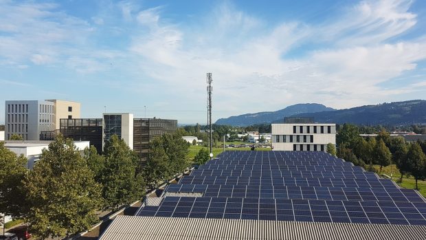 Photovoltaic solar panels cover a large flat urban rooftop