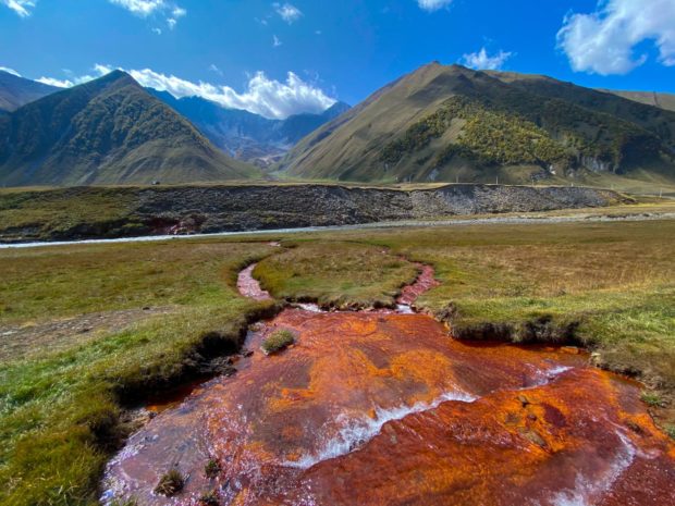 Photograph of a river where the water has an orange/red colour because of high iron content