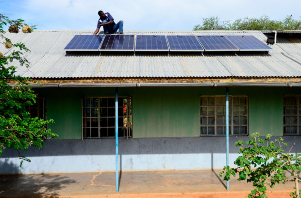 Image of solar panels being installed on a roof (in Uganda)