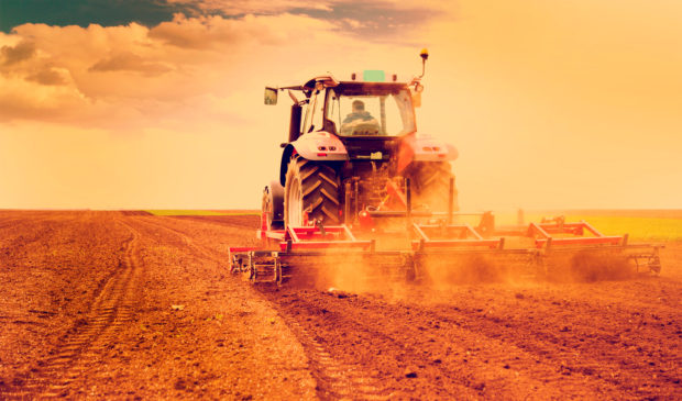 Tractor being driven through a dusty landscape