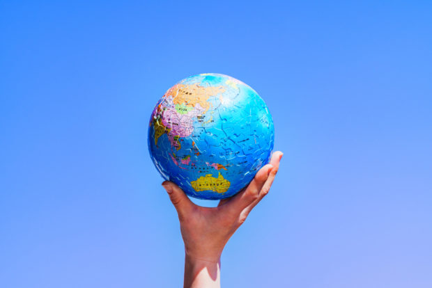 Hand holding a spherical jigsaw in the shape of the world, to symbolise global interconnectedness and the kyoto protocol