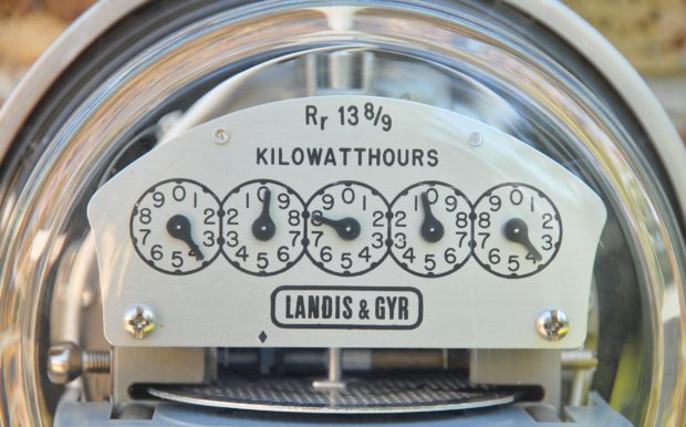 Photograph of old-fashioned electricity meter with a glass front and six dials showing different readings in kilowatt hours