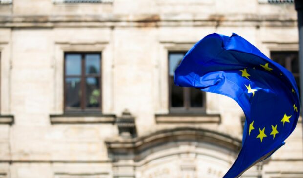 EU flag blowing in the breeze in front of a historic-looking building